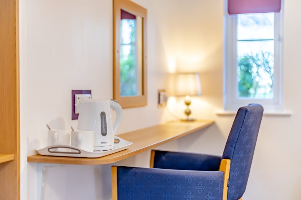 Seating area by mirror with kettle in a cottage bedroom